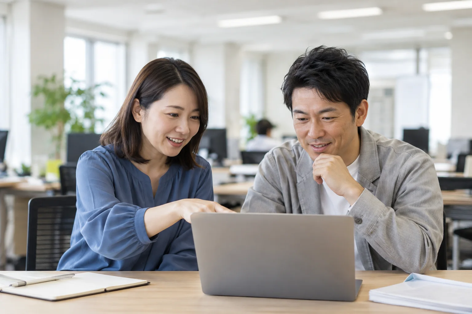 パソコンを見ながら話す同僚たち